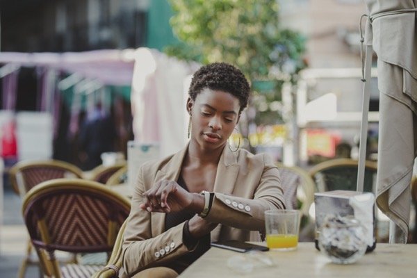 Black woman checking time and sitting at table wit 2023 11 27 05 03 17 utc.