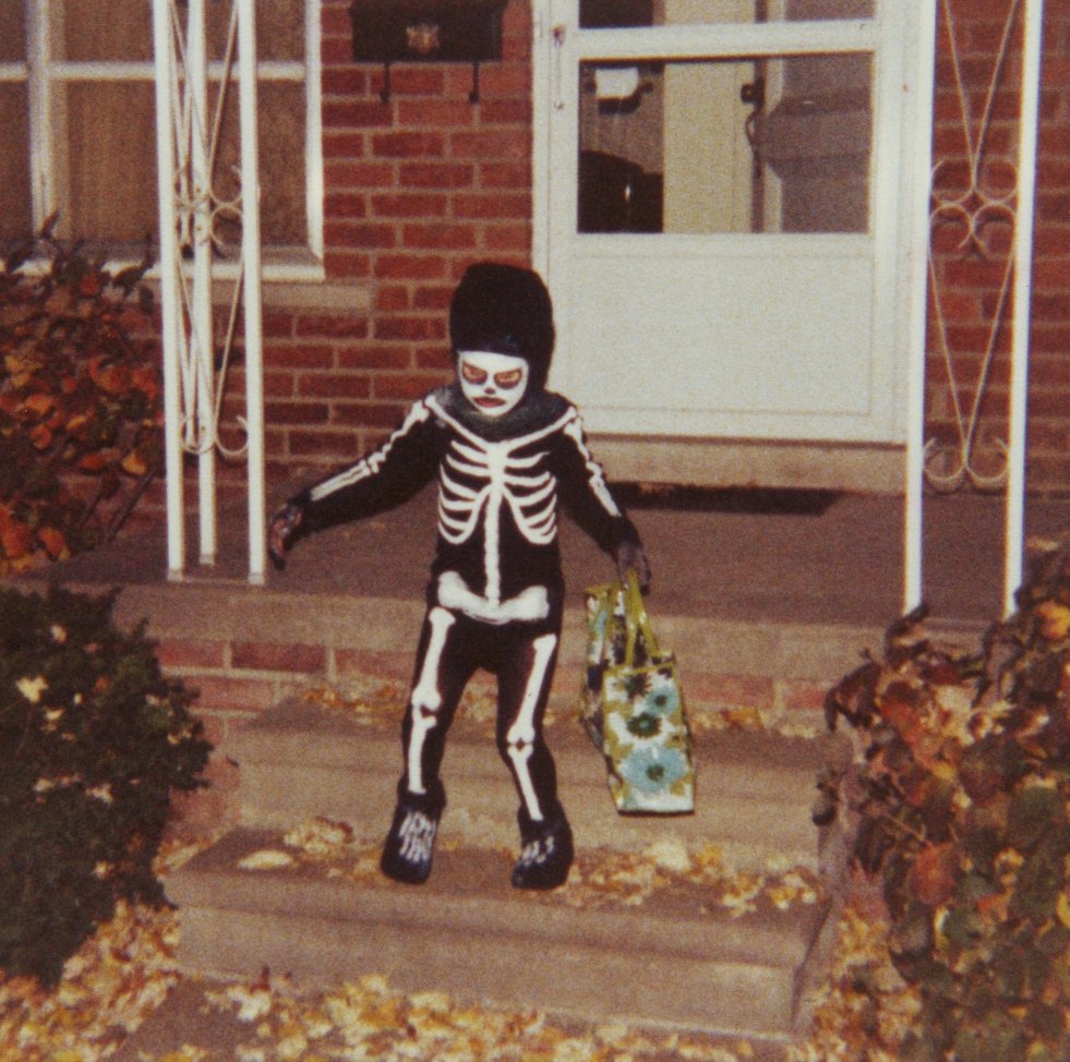 Child in a Halloween costume trends 2026 style witch outfit holding a trick-or-treat pumpkin bucket