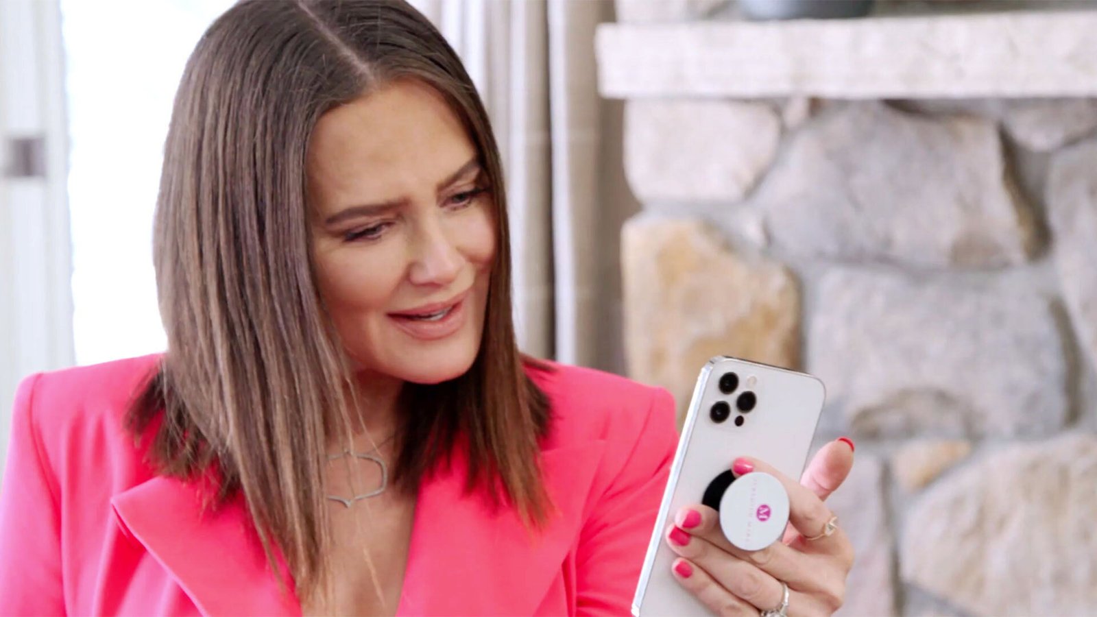 Meredith Marks in a pink blazer looking at her phone