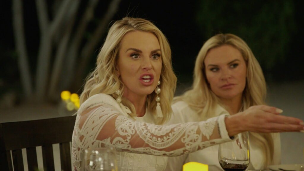 Whitney Rose gesturing mid-argument at an outdoor dinner table, Heather Gay beside her