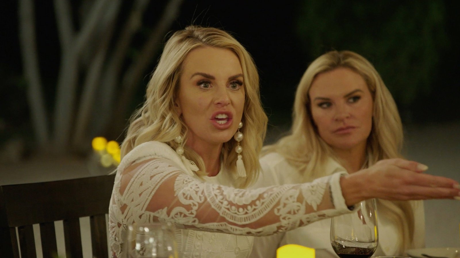 Whitney Rose gesturing mid-argument at an outdoor dinner table, Heather Gay beside her