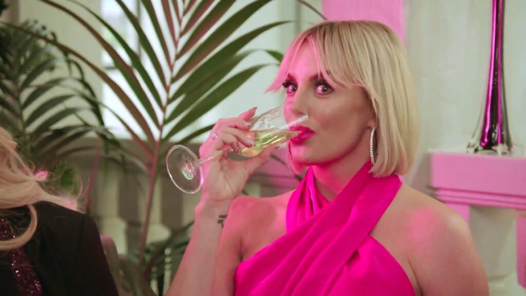 Whitney Rose sipping champagne in a pink dress at the casino-night fundraiser in The Real Housewives of Salt Lake City