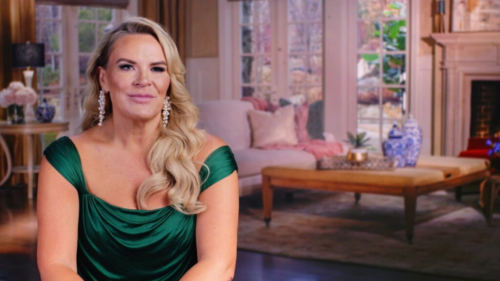 Heather Gay in an emerald dress and pearl-drop earrings, smiling in a confessional-style shot