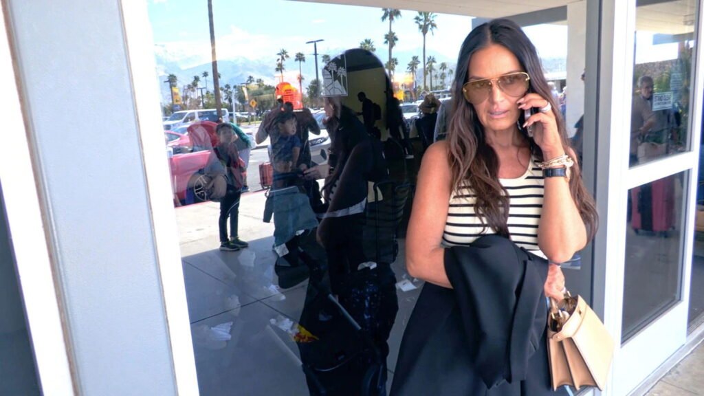 Lisa Barlow in aviator sunglasses, on the phone outside the airport in Palm Springs