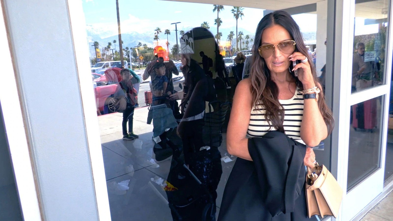 Lisa Barlow in aviator sunglasses, on the phone outside the airport in Palm Springs