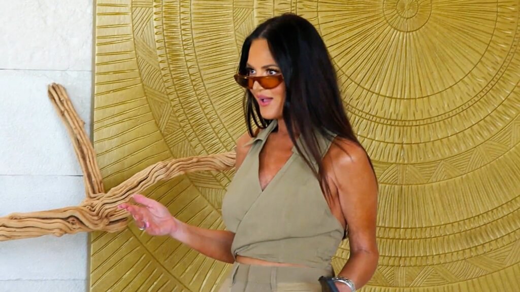 Lisa Barlow gesturing in front of a gold sunburst wall