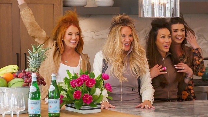 The women in big tribute hairstyles gathered around a kitchen island