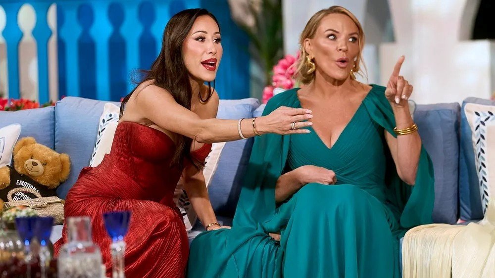 Lisa Barlow reaching toward Heather Gay on the reunion couch, mid-exchange