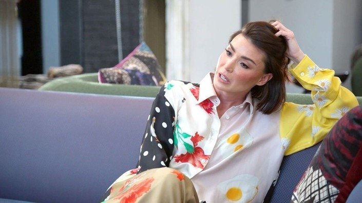 Bronwyn Newport reclining on a couch in a printed shirt