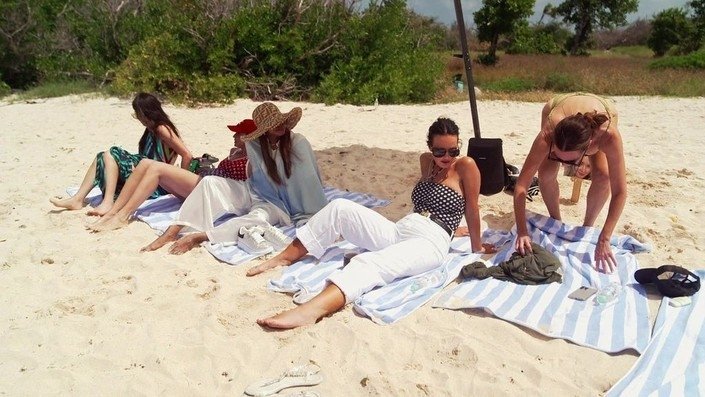 The women relaxing on towels on the beach in Canouan