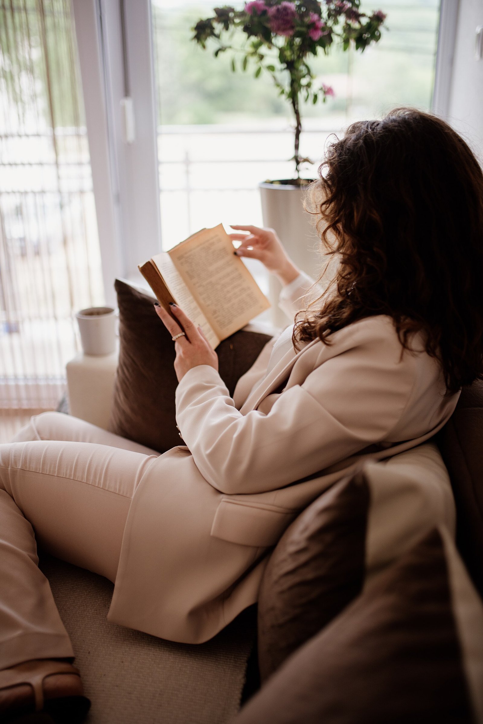 A young person curled up at home with a book and a mug, illustrating soft hermitting Gen Z and the deliberate night in